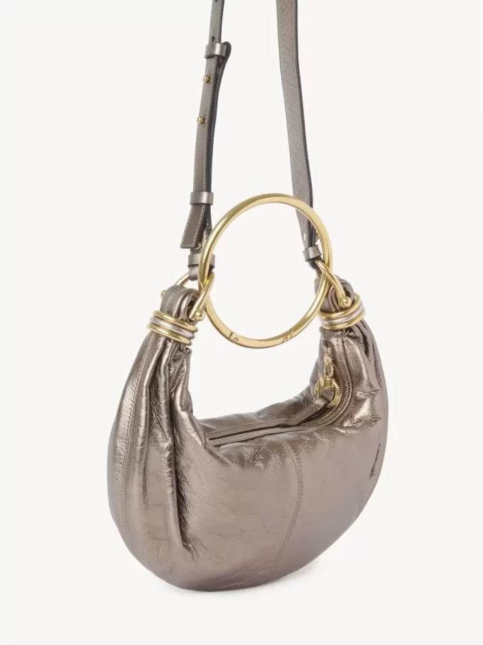 Kleine Hobo-Tasche mit Armband aus metallisiertem Leder Kleine Hobo-Tasche mit Armband aus metallisiertem Leder